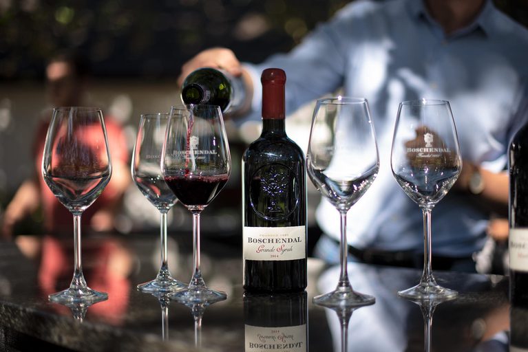 Wine glasses and red wine bottle, hand pouring wine into a glass.