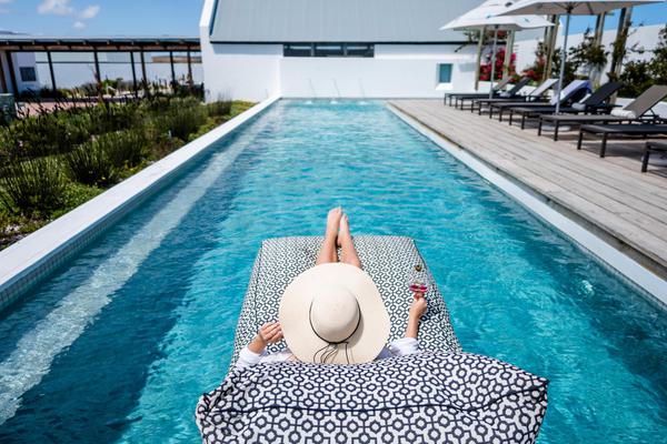 Turquoise pool with person on lounger.