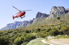 Red Helicopter landing at The Twelve Apostles, Cape Town with mountain backdrop