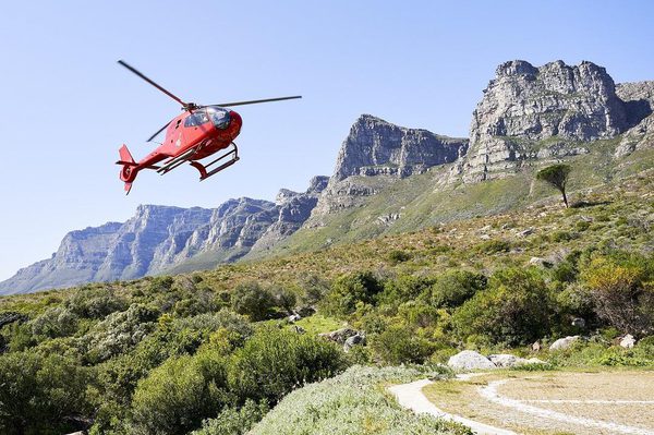 Red Helicopter landing at The Twelve Apostles, Cape Town with mountain backdrop