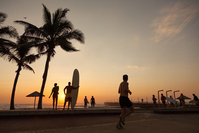Sunset surfer and runner with palm tree Durban Coast KZN SAT