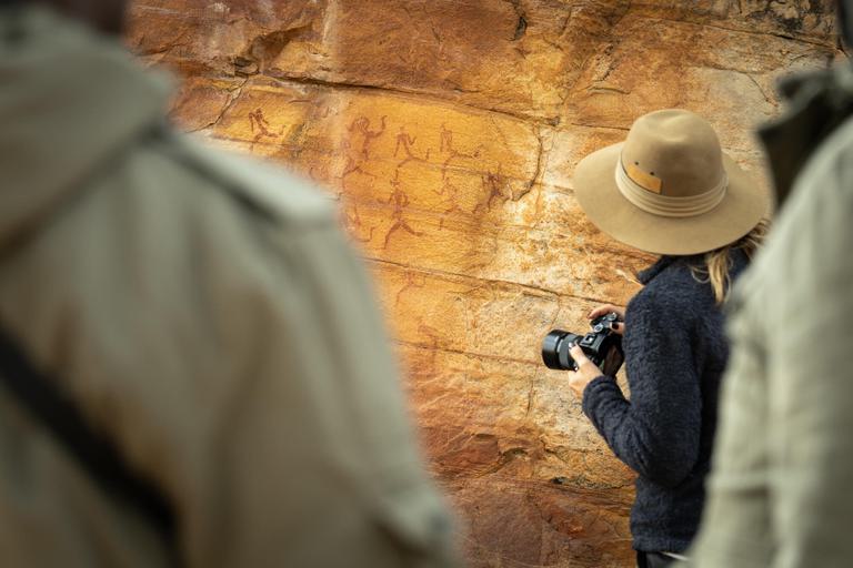 Woman looking at rock art with camera Singita Pamushana Zimbabwe