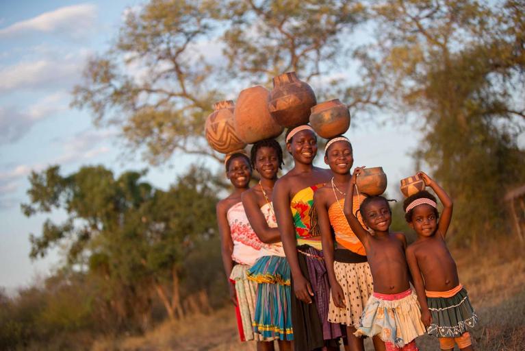 Community visit ladies and children with calabash on head Singita Pamushana