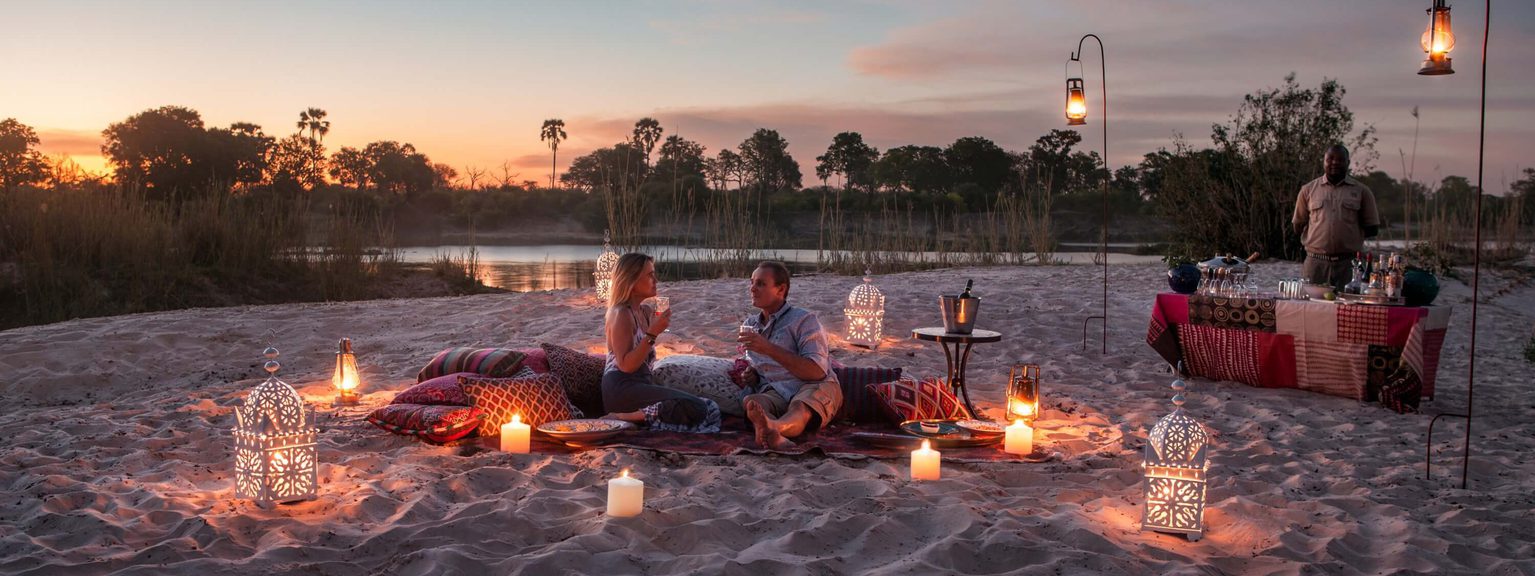 Couple sunset picnic on sandbar Tongabezi