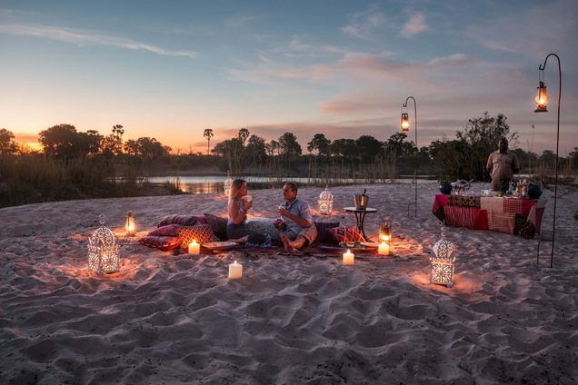 Couple sunset picnic on sandbar Tongabezi