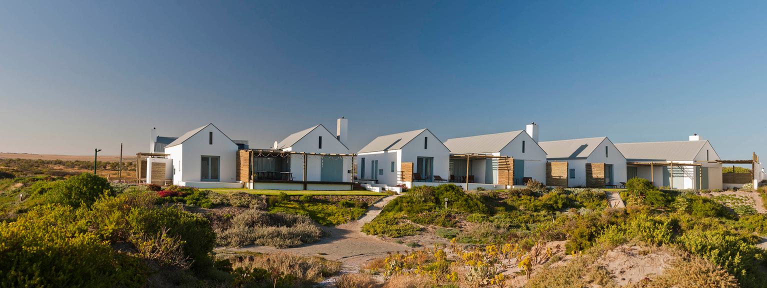 Wooden small buildings, grass, sand and dark blue sky,