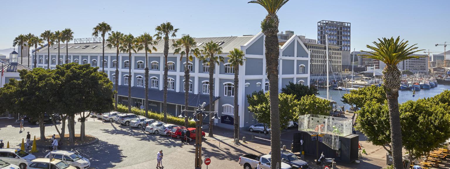 Hotel with iconic blue exterior and many white-framed windows, and palm trees.
