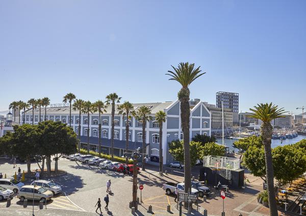 Hotel with iconic blue exterior and many white-framed windows, and palm trees.