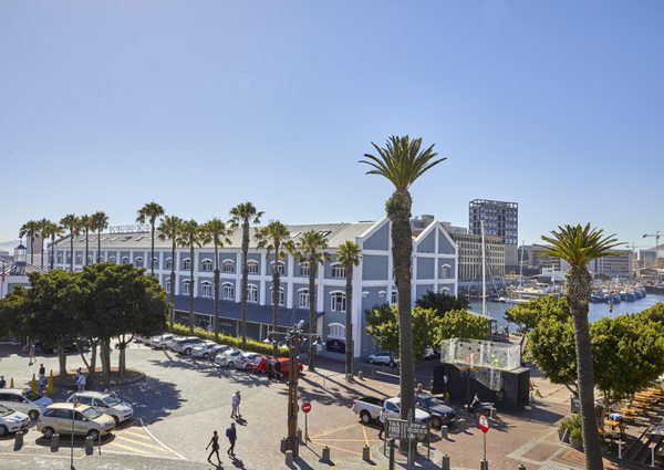 Hotel with iconic blue exterior and many white-framed windows, and palm trees.
